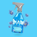 A bottle of Astonish Linen Fresh ready-to-use disinfectant spray, shown against a bright blue background with decorative blue flowers floating around it.