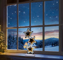 A decorative three-tiered star night light with glowing warm gold centers and white LED outlines stands on a windowsill. Outside the window, a snowy winter landscape with mountains and a starry night sky is visible.